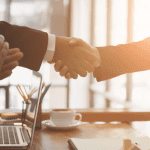 Two people shaking hands over a laptop computer for the most trusted payday loans online