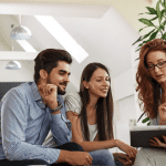 Three people sitting on a couch looking at a tablet reading about payday loan relief