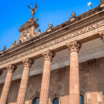 A large government building with columns and a statue on top of it representing help with payday loans