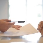 Two people discussing payday loans in Mississippi over a table with paperwork.