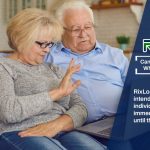 A man and woman sitting on a couch looking at a laptop reading how to obtain a payday loan while receiving benefits