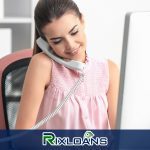 A woman talking on a phone while sitting in front of a computer searching for payday loans Virginia