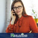 A woman sitting at a desk talking on a cell phone about payday loans Washington