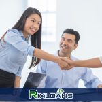 A group of people shaking hands over a table after discussing the main features of a payday loan