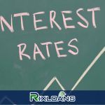 A hand writing interest rate on a chalkboard