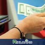 A person holding a dollar bill obtained from a payday loan in Alabama in front of a machine