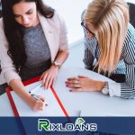 Two women sitting at a table with a pen and paper to find out the number of payday loans they can have in New York