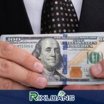 A man in a suit holding a stack of money while looking for ways to consolidate payday loans in Indiana