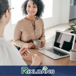 Two women sitting at a table with a laptop discussing the differences between a payday loan and installment loan