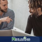 Two men sitting at a table looking at a laptop reading about payday loans in Chicago