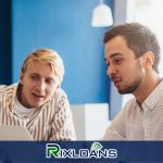 Two men sitting at a table looking at a laptop comparing payday loans in Denver