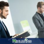 A man in a suit and tie standing next to another man in a suit reading about payday loans in San Diego