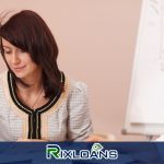 Two women sitting at a table writing on a piece of installment loans agreement paper in Arkansas