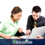 A man and woman sitting on a couch looking at a laptop reading about installment loans Colorado