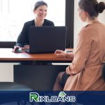 A woman sitting at a table with a laptop in front of her applying for installment loans Delaware