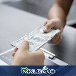 A person handing installment loans money to another person in front of a laptop in Oregon