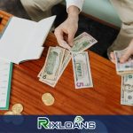 A person sitting at a desk with money from installment loans Rhode Island and a notebook