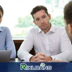 A man and woman sitting at a table with a laptop discussing installment loans Alabama